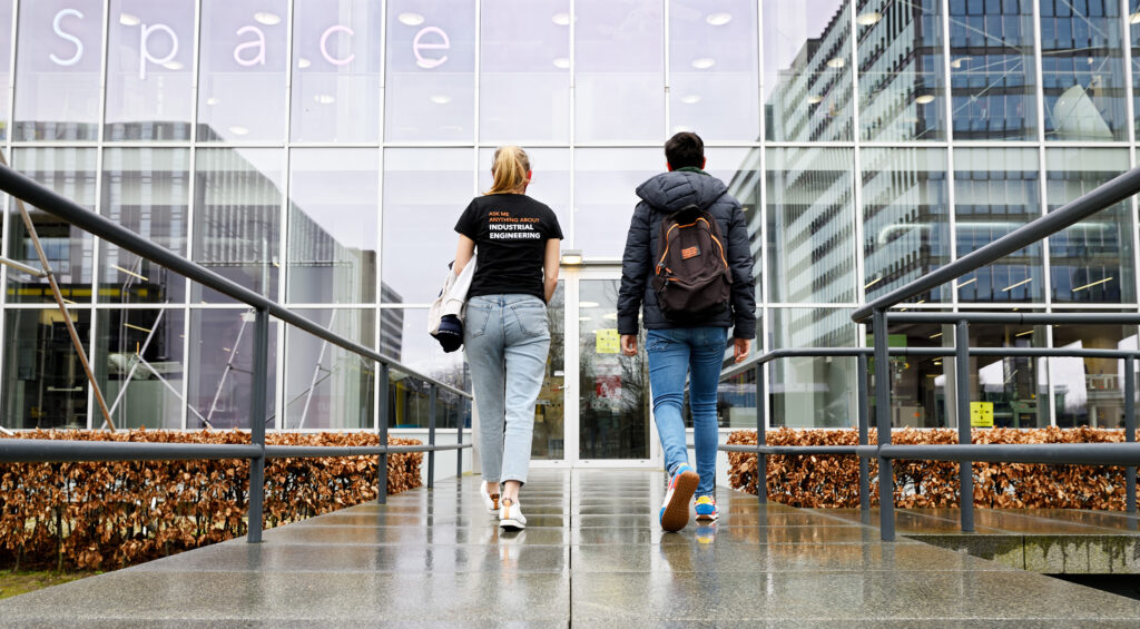 A female student showing a male student around, explaining how he can participate in different activities at Eindhoven University of Technology.