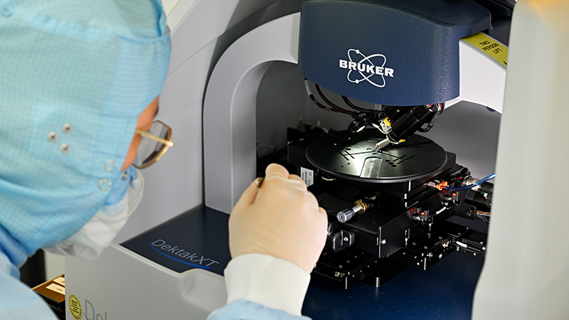 Yi Wang, Photonic Integration, Electrical Engineering, TU Eindhoven, with InP-based photonic integrated circuits in a step profilometer (Bruker DektakXT). Photo: Bart van Overbeeke Photography